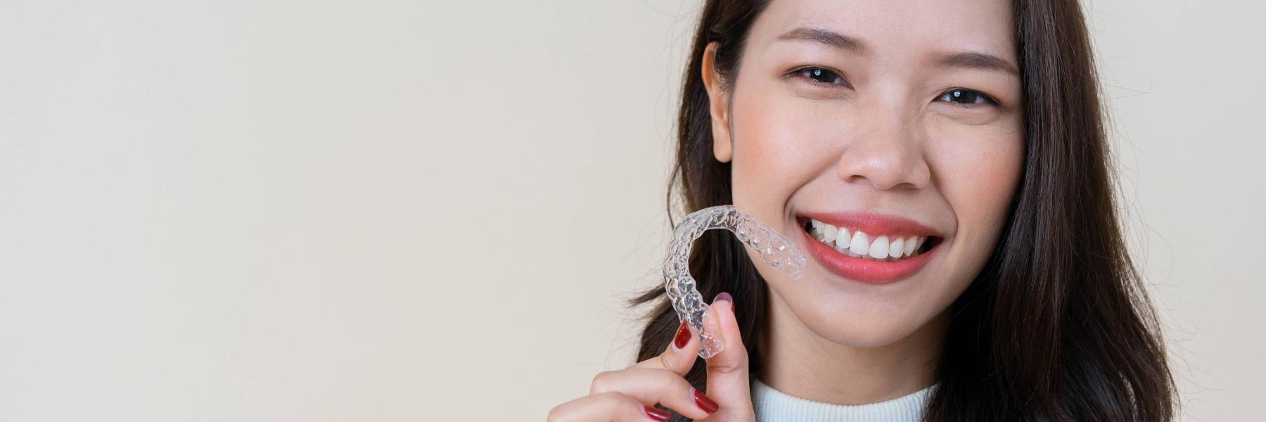 woman holding up her invisalign in jonesboro ar