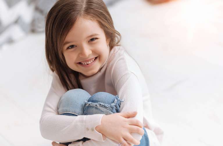 A smiling girl hugging her knees